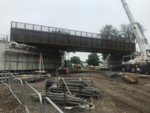 A wide shot of the Alton rail bridge being installed onto concrete base.